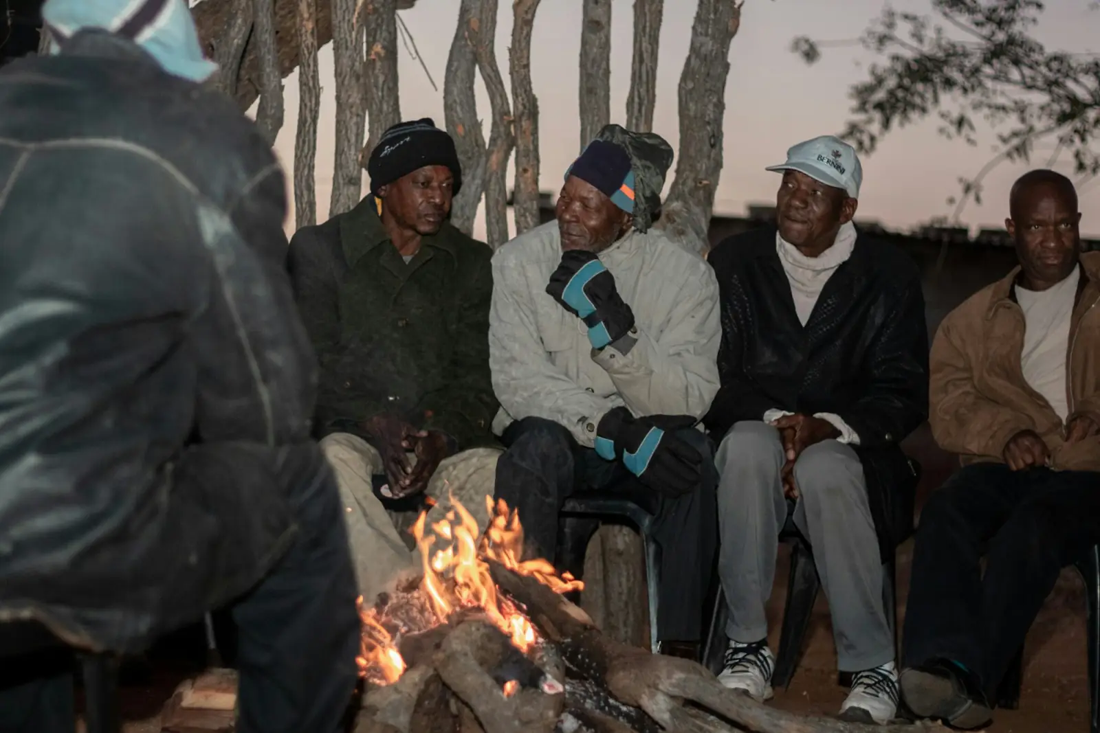 Guides and guests around a campfire at a safari camp