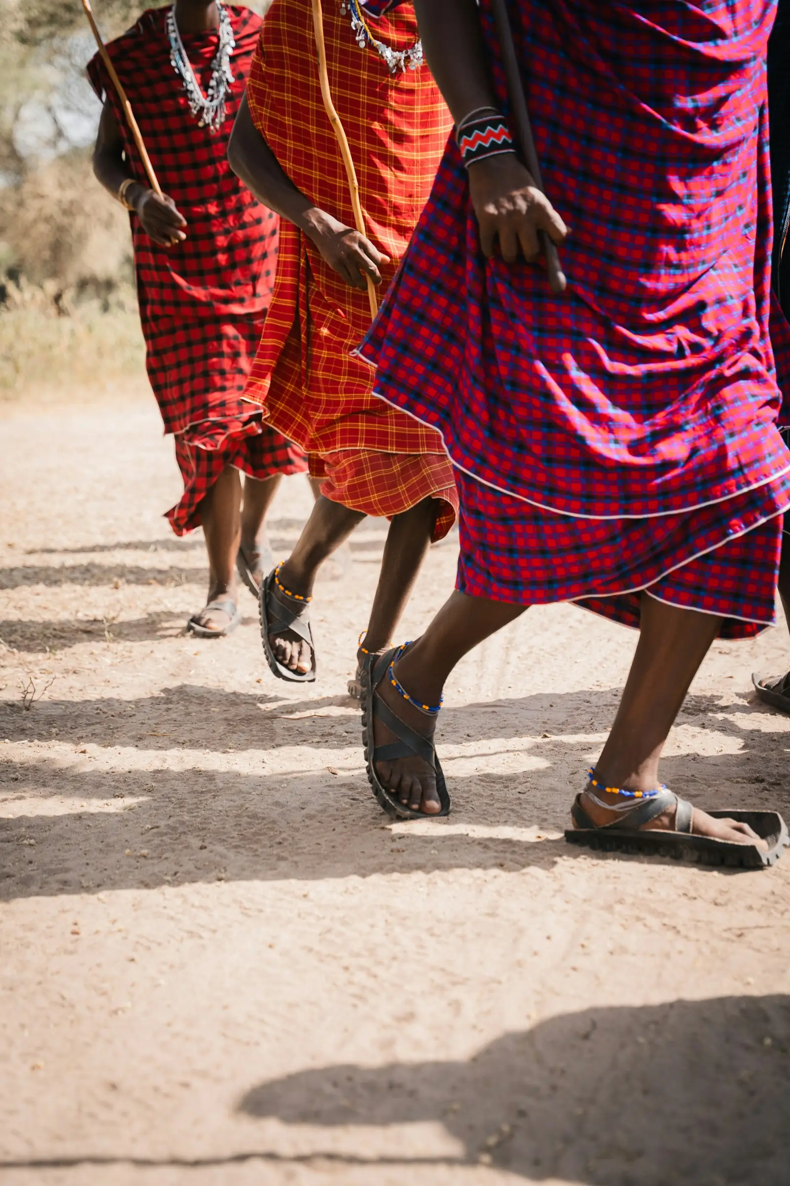 Maasai men in red shukas walking along a dirt road