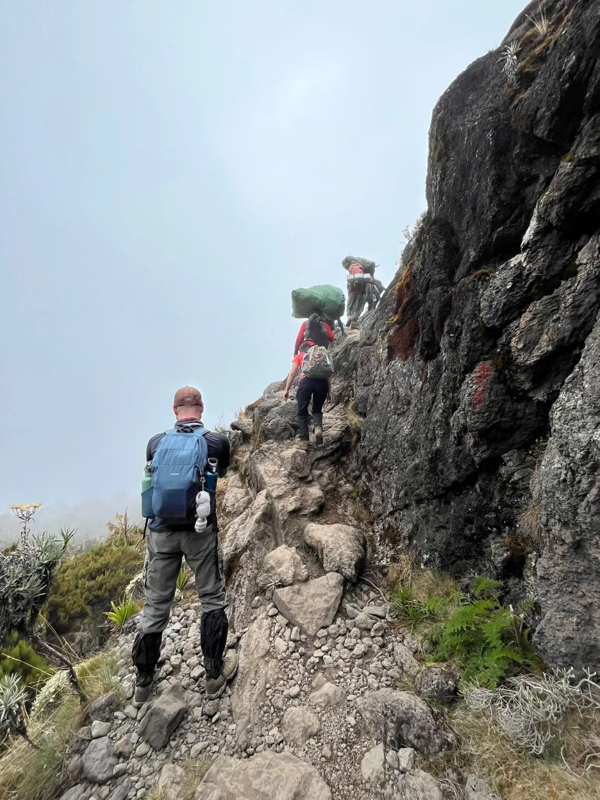 Trekkers climbing the rock of the Barranco Wall with packs on