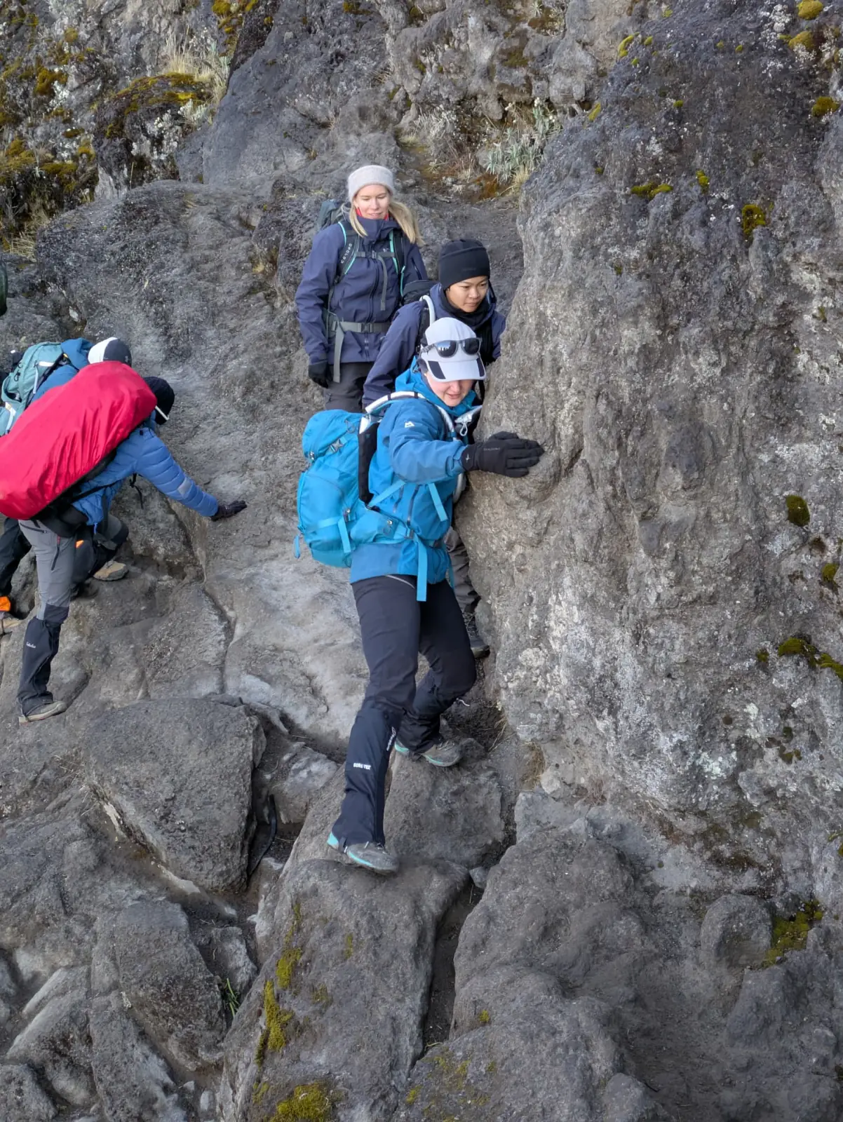 Trekkers picking their way up a steep rock section in cold weather gear