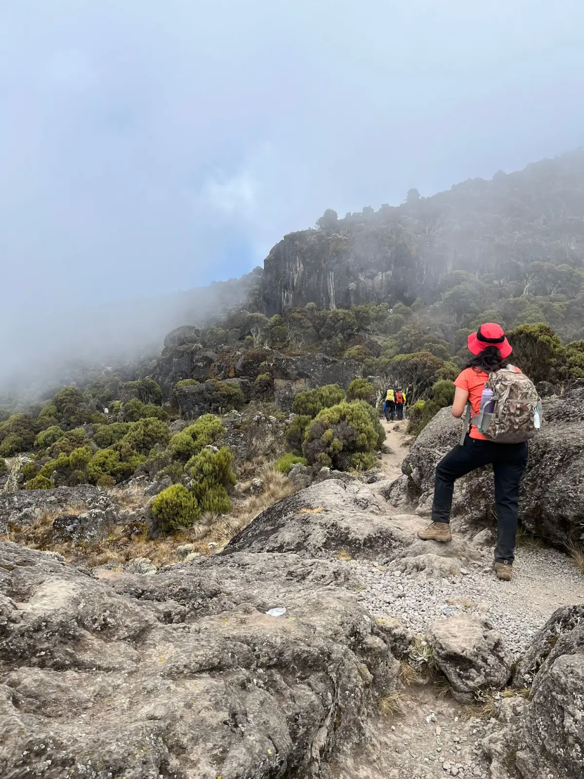 A trekker resting on rocks in thick cloud high on the mountain