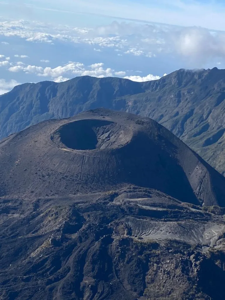 The ash cone inside the Mount Meru crater, seen from the rim with the crater wall behind