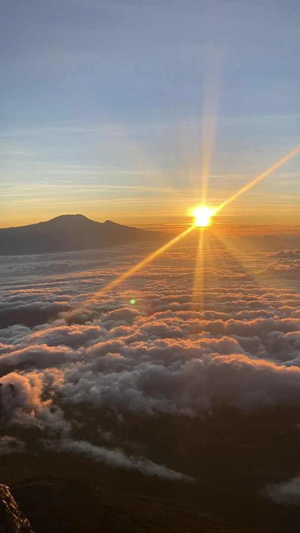 Sunrise seen from high on Mount Meru, with Kilimanjaro silhouetted above a sea of cloud