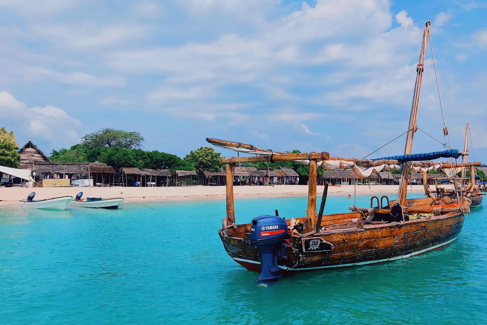 A wooden dhow moored off a white Zanzibar beach